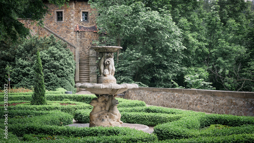 Formal Garden with a Fountain and a Stone Building.
