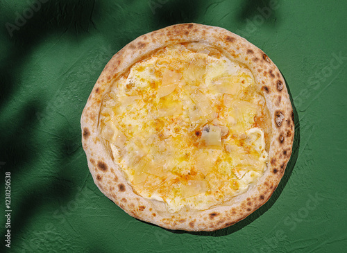 Delicious white pizza topped with cheese and potatoes on a vibrant green background photo