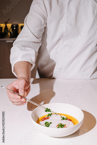 Fototapeta Naklejka Na Ścianę i Meble -  Culinary artist plating a gourmet dish with precision in a modern kitchen at twilight