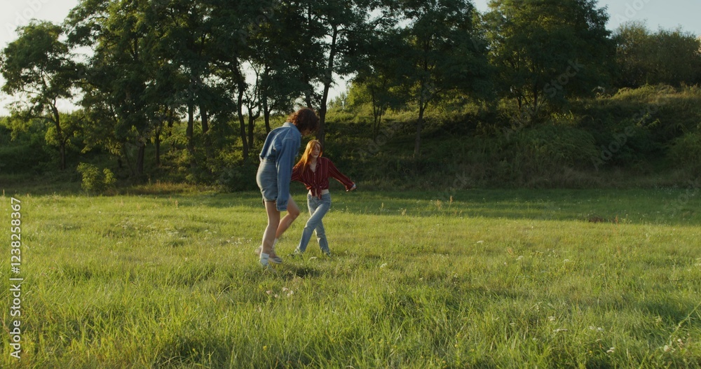 Two women are jumping and having fun standing in a meadow on a summer day. Summer holidays, carefree time Two women are jumping and having fun standing in a meadow on a summer day. Summer holidays, carefree time