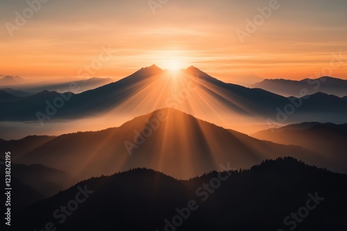 Golden sunrise over mountain peaks with radiant sunbeams and layered misty valleys