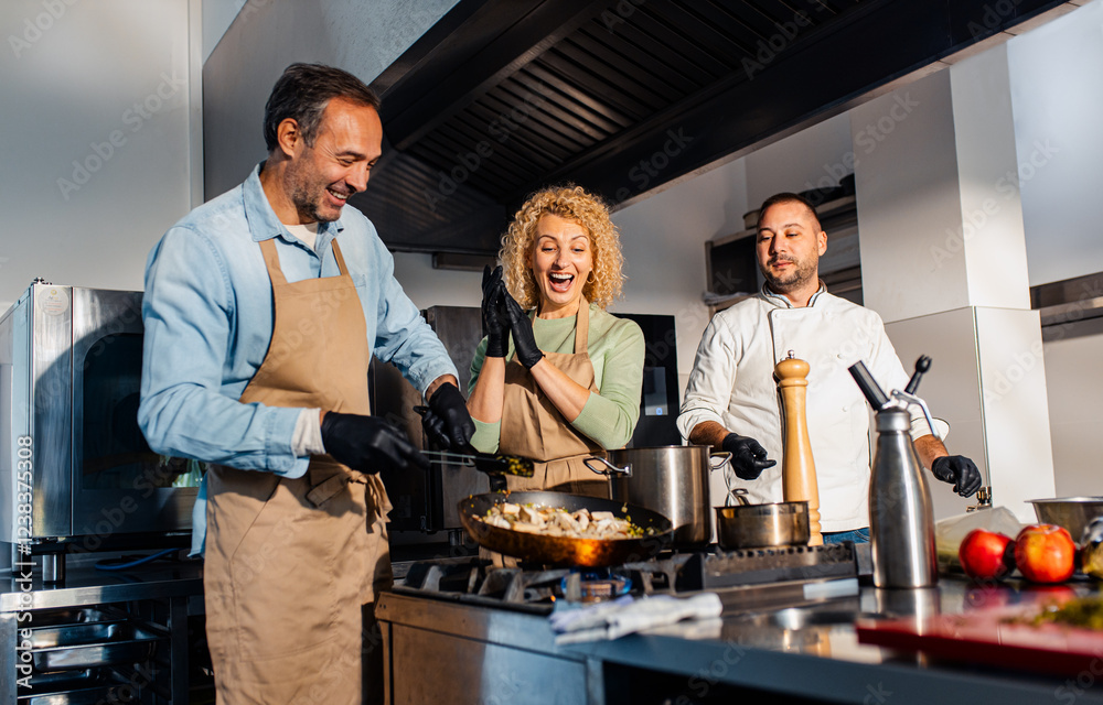 Couple enjoying a cooking class with a chef preparing meal in the kitchen. Couple enjoying a cooking class with a chef preparing meal in the kitchen.
