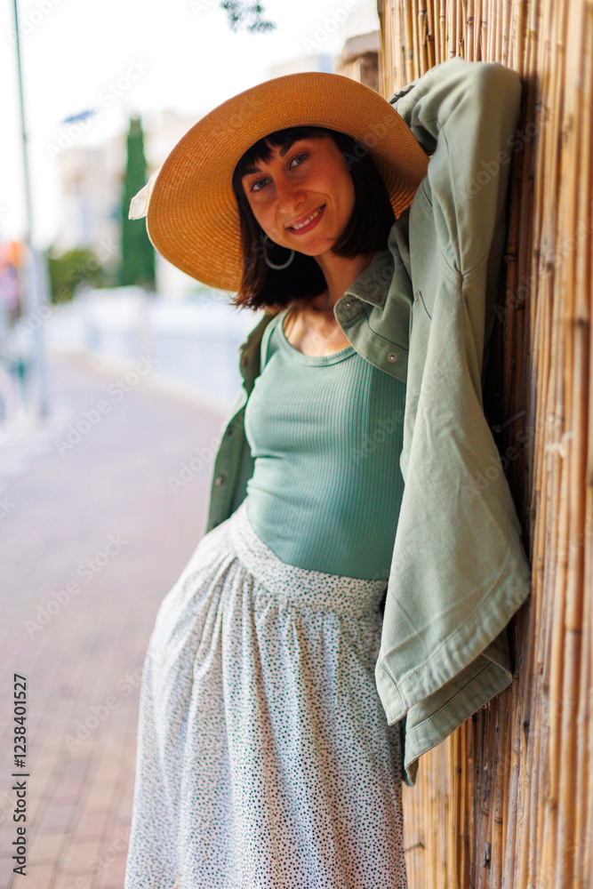 Obraz premium Young girl smiling happy standing at the city. portrait of a beautiful brunette in stylish summer clothes. Cheerful young woman smiling on the street during vacation.