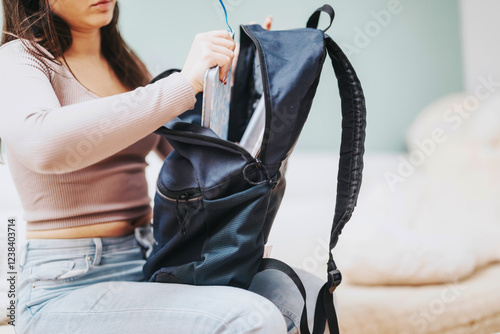 Canvas Print A student is inserting a laptop into her backpack, getting ready for a day of work or study