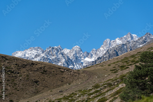 Kabardino-Balkaria. Majestic natural landscapes of Elbrus region against backdrop of blue autumn sky. View of snow-capped peaks of Chegem Gorge. Steep cliffs covered in snow and ice rise upward. photo