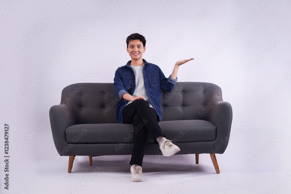 Full body image of young Asian man posing on sofa on white background Full body image of young Asian man posing on sofa on white background