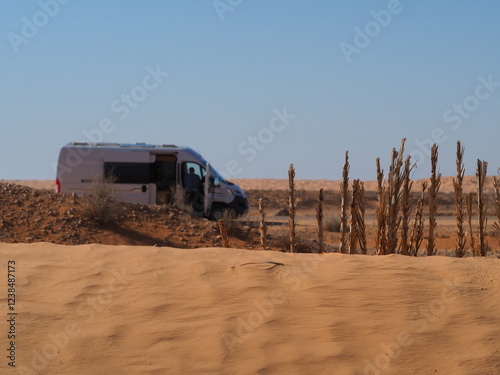 A camper van standing by the sand dunes of the Sahara Desert in Tunisia photo