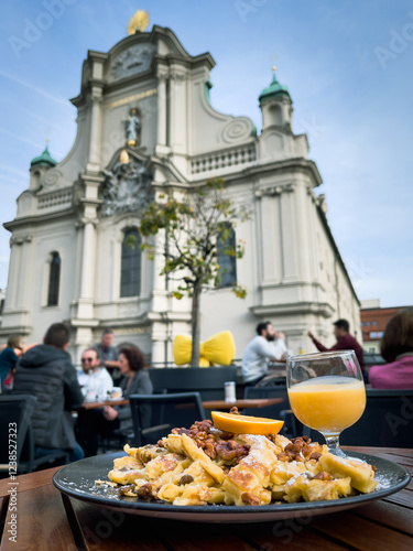 Traditional emperor’s mess  scrambled pancake with views of Holy Spirit Church on background in Munich. European tourism, gastronomy tour concepts