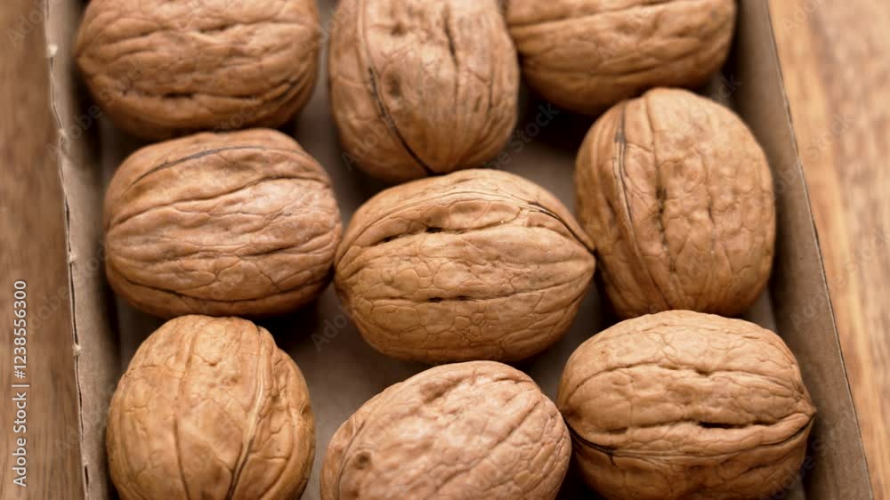 Group of raw walnuts in biodegradable cardboard packaging on wooden table. Organic food. Rotation. Top view Group of raw walnuts in biodegradable cardboard packaging on wooden table. Organic food. Rotation. Top view