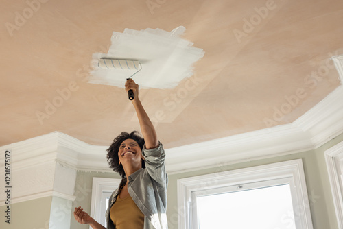 Happy Woman Applying Paint to Ceiling with Roller photo