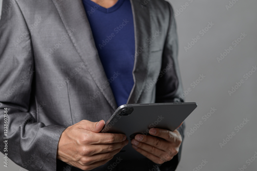 Professional Man in Suit Holding Tablet with Gray Background Professional Man in Suit Holding Tablet with Gray Background