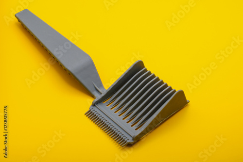 Single lice comb isolated on a yellow surface.  Tool for detecting and eliminating head lice, promoting scalp health and preventing infestations.