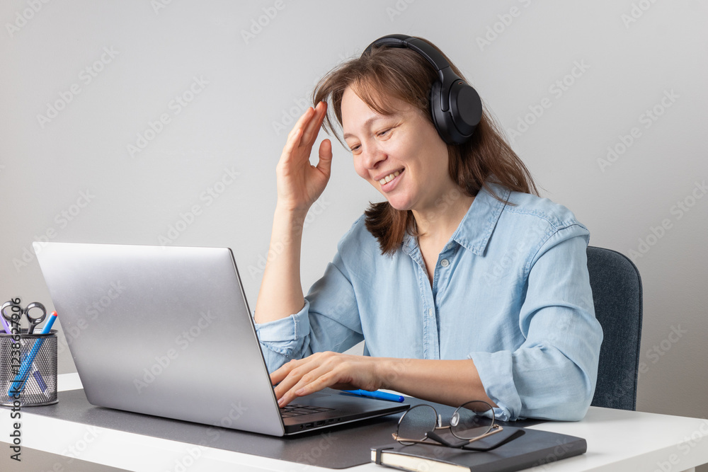 A cheerful smiling woman with headphones using laptop, looking at PC screen, remote hardworking freelancer works from home. Correct posture, happiness o be a freelancer A cheerful smiling woman with headphones using laptop, looking at PC screen, remote hardworking freelancer works from home. Correct posture, happiness o be a freelancer
