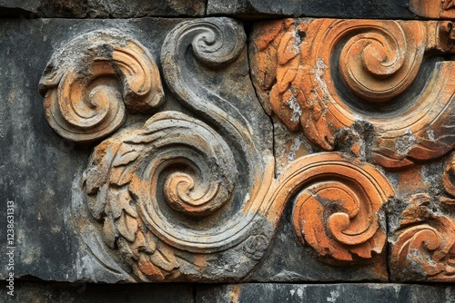 Intricate swirling stone carvings adorn ancient weathered wall, showcasing ornate detailing and aged texture. photo