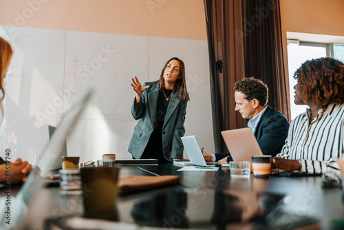 Businesswoman discussing strategies with colleagues sitting on board room