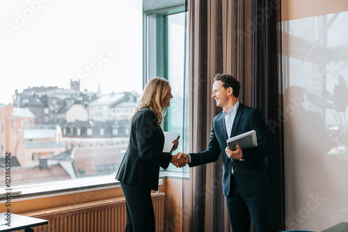 Happy male and female business professionals doing handshake at office