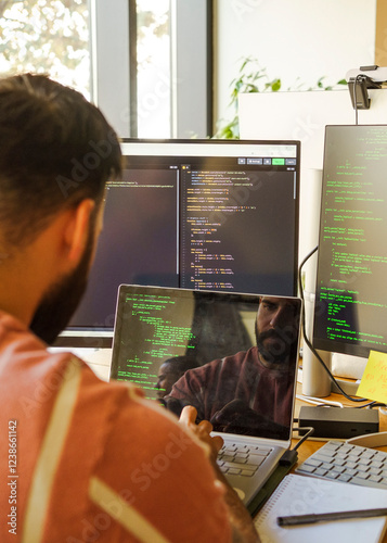 Male IT professional coding on laptop in tech startup office photo