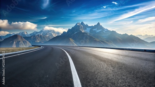 Asphalt road curving gently towards majestic snow-capped mountains under a vibrant sky