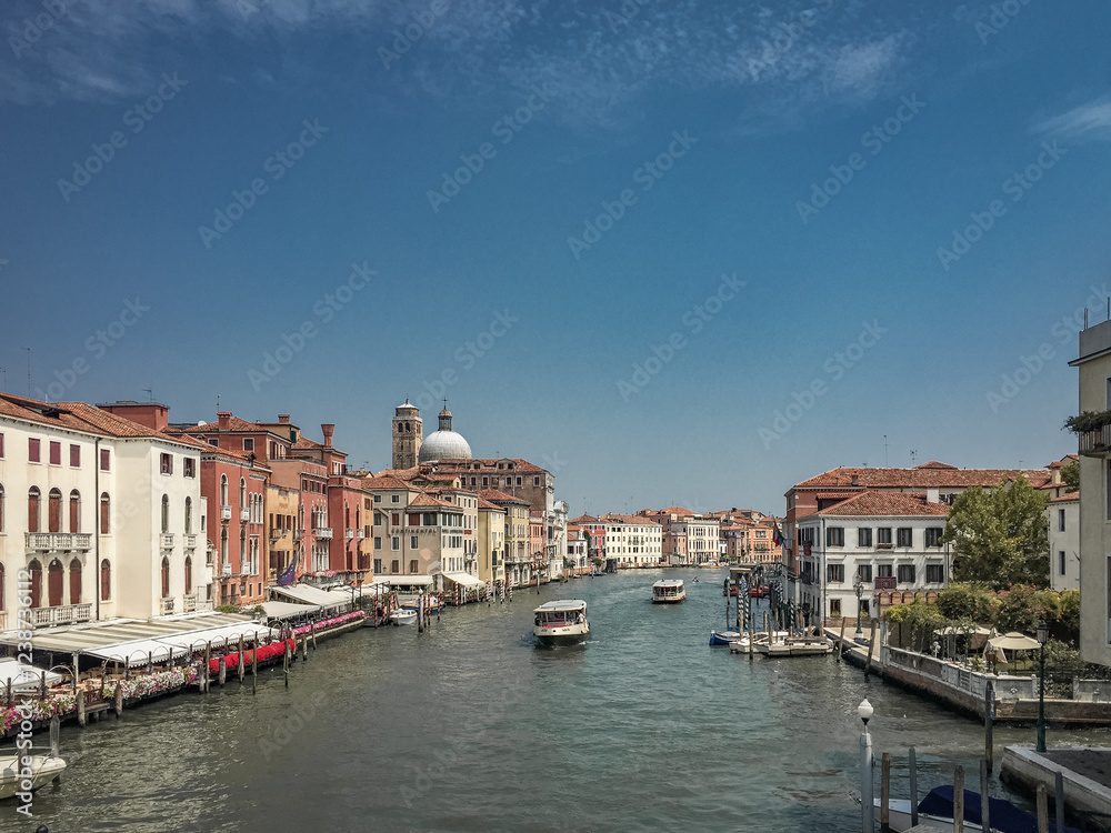 A Sunny Day on the Grand Canal. The canal stretches into the distance, lined with colorful buildings and dotted with boats. The sky is a brilliant blue, adding to the cheerful atmosphere. A Sunny Day on the Grand Canal. The canal stretches into the distance, lined with colorful buildings and dotted with boats. The sky is a brilliant blue, adding to the cheerful atmosphere.