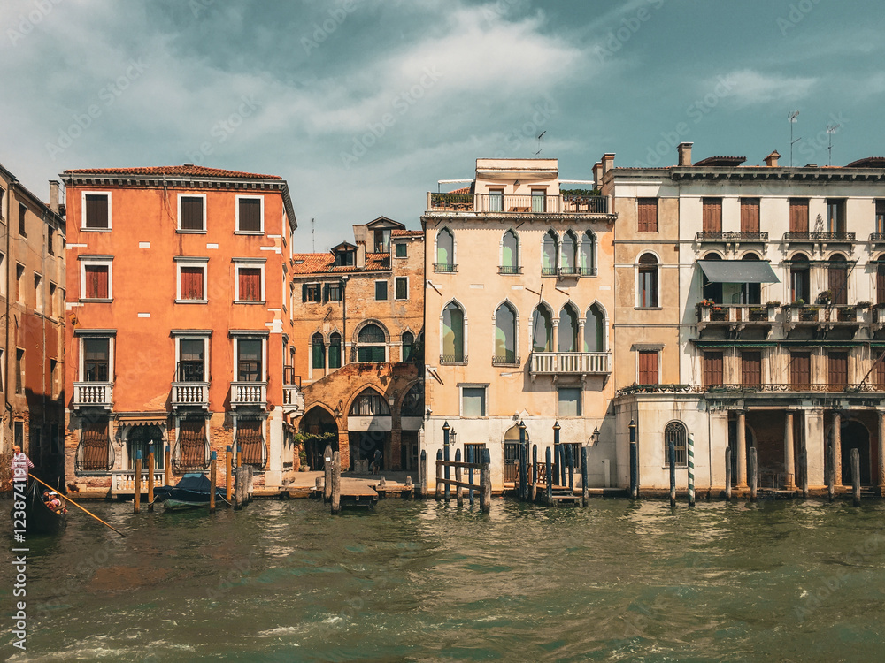 Venetian Canal with Colorful Buildings. A canal winds its way through the city, lined with colorful buildings in various shades of orange and yellow. The sky is a mix of blue and fluffy white clouds. Venetian Canal with Colorful Buildings. A canal winds its way through the city, lined with colorful buildings in various shades of orange and yellow. The sky is a mix of blue and fluffy white clouds.