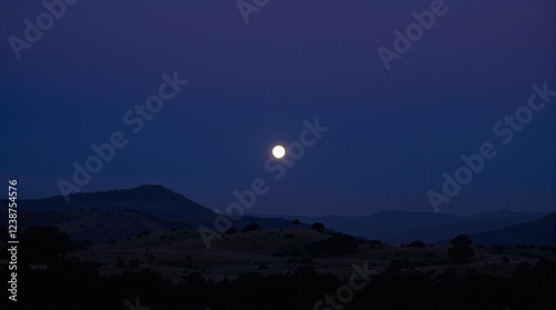 Full moon rising over serene mountains, tranquil and enchanting, under night sky