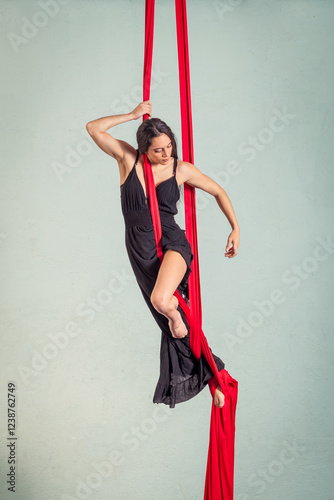 Aerialist performing poses on red aerial silks photo