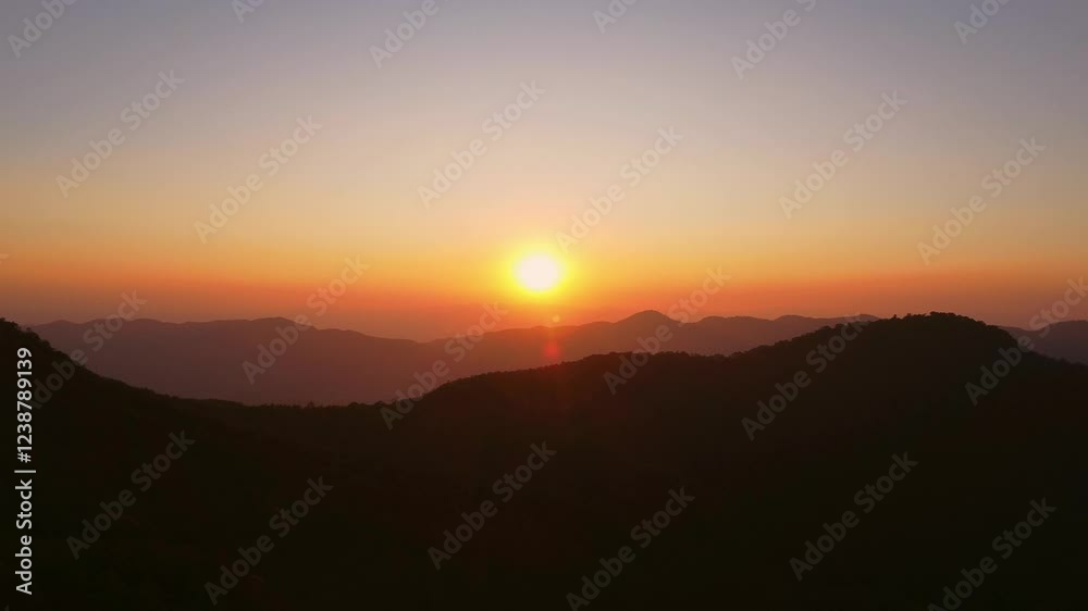 Beautiful sunset in the winter mountains. The setting sun shines down on a serene mountain landscape covered with tropical trees in the evening. Beautiful sunset in the winter mountains. The setting sun shines down on a serene mountain landscape covered with tropical trees in the evening.