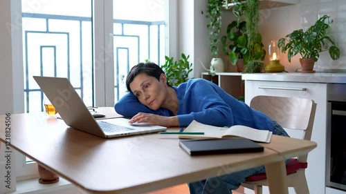 Tired scattered mature woman working at laptop at home, resting on hand. Bored disinterested adult student struggling, feel sleeplessness, headache, scrolling mindlessly, search information for study