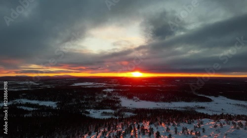 Aerial drone footage of bright and colorful sunset during golden hour over winter forests and top of snow covered mountain in Pallas-Yllästunturi National Park Lapland, Finland
 photo