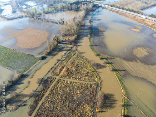 Vue aérienne prise avec un drone montrante rivière en crue qui déborde et un paysage inondé.