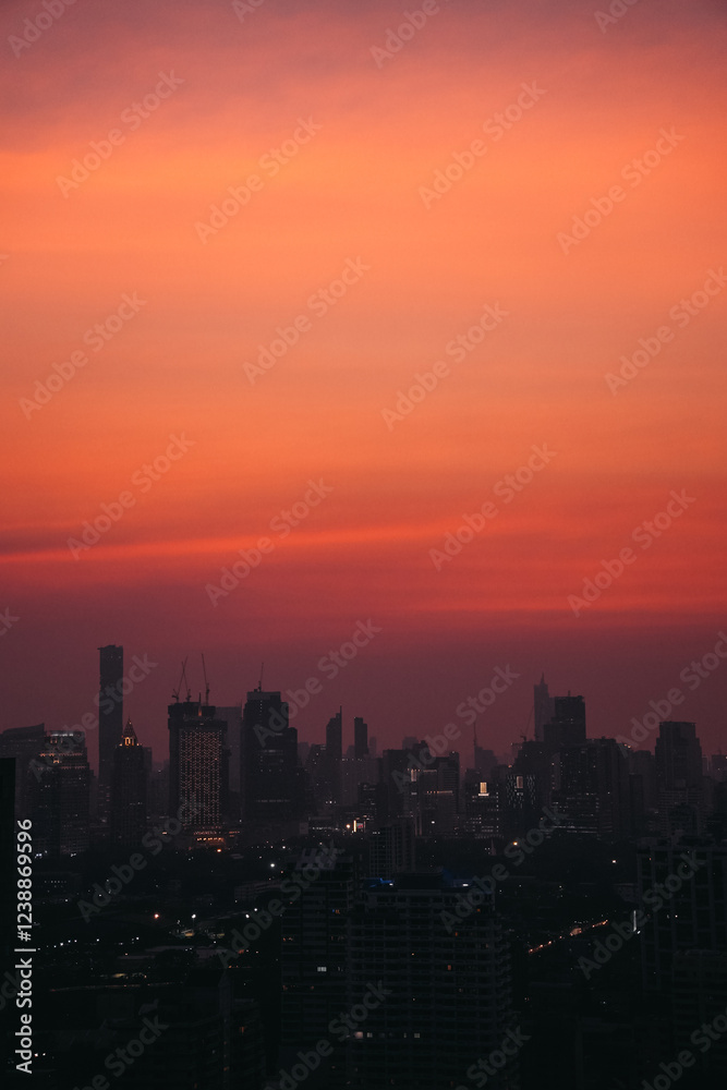 Obraz premium Dark silhouettes of Bangkok's buildings rising against an expressive, intense orange sunset sky, creating a dramatic urban landscape, Thailand