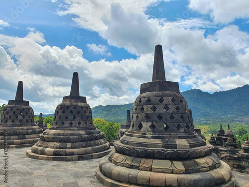 Ancient Stone Structures of Borobudur Temple at Magelang. Exploring the Architectural Marvels of a Historic Temple Complex under a Cloudy Sky, Intricate Stonework and Cultural Heritage