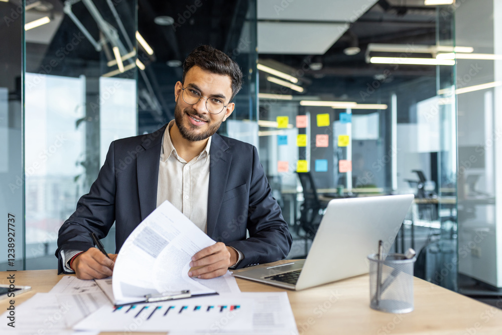Portrait of successful financier, man signs documents reports contracts. Businessman at workplace inside office doing paper work, filling out tax and statistical forms, looking at camera smiling. Portrait of successful financier, man signs documents reports contracts. Businessman at workplace inside office doing paper work, filling out tax and statistical forms, looking at camera smiling.