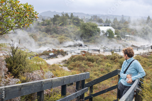 Tourist admiring steaming geothermal landscape in rotorua, new zealand