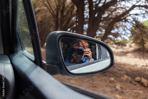 Photographer taking photos from car window reflected in side mirror