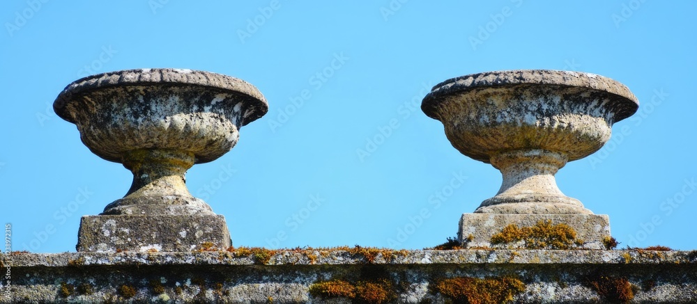 Stone urns on a wall with moss against a clear blue sky in a historic architectural setting Copy Space Stone urns on a wall with moss against a clear blue sky in a historic architectural setting Copy Space