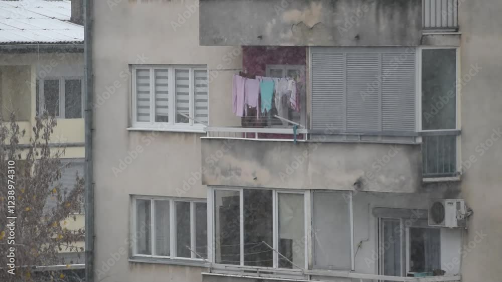 Clothes hanging on clothesline on residential building balcony during snowfall Clothes hanging on clothesline on residential building balcony during snowfall