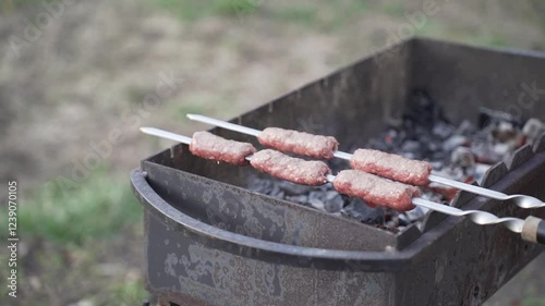 Food cooked outdoors on charcoal, hands in frame. Barbecue.