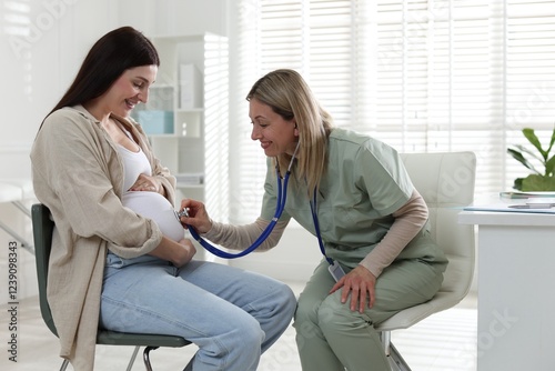 Pregnancy checkup. Doctor with stethoscope listening baby's heartbeat in patient's tummy indoors photo