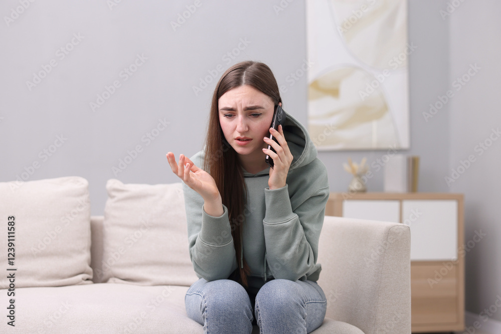 Depressed woman calling hotline for mental health help on sofa at home Depressed woman calling hotline for mental health help on sofa at home