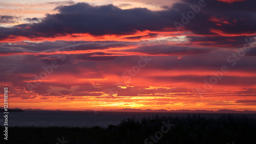 Fototapeta Naklejka Na Ścianę i Meble -  A breathtaking sunset paints the sky with vibrant shades of red, orange, and purple over a serene coastal landscape. 