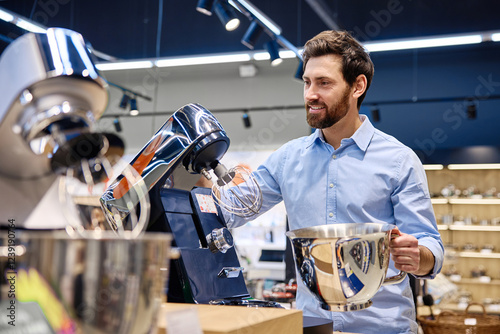 A man is currently demonstrating a kitchen stand mixer in a large electronics store showroom