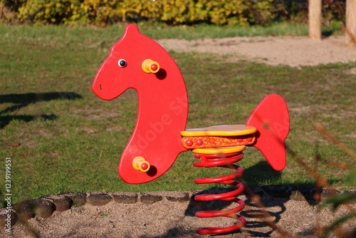 Close-up of a red rocking horse with a red spring on the playground