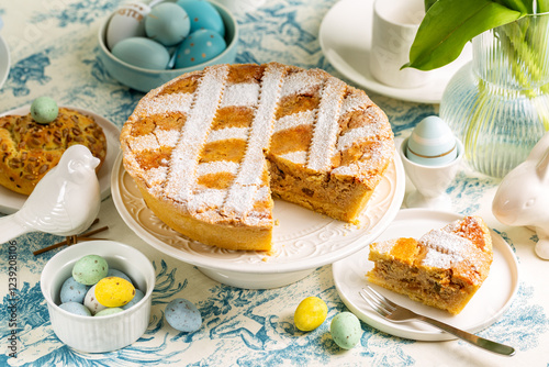 Obraz na płótnie Italian Easter cake Pastiera Napoletana, shortcrust pie with ricotta cheese filling and cooked grains, colorful eggs, buns, vase with tulips