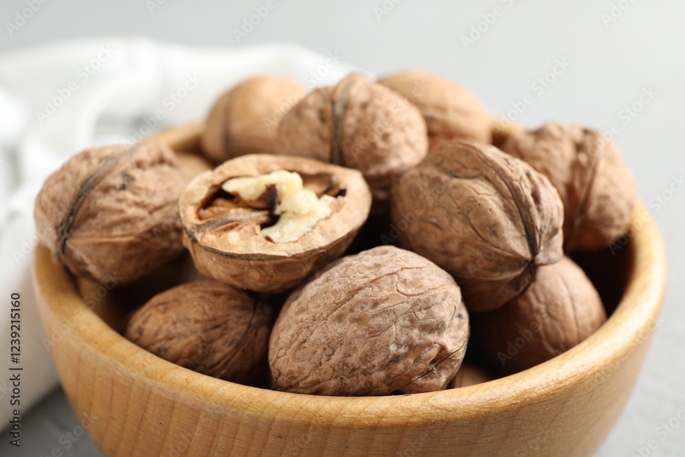 Fresh walnuts in bowl on gray table, closeup Fresh walnuts in bowl on gray table, closeup
