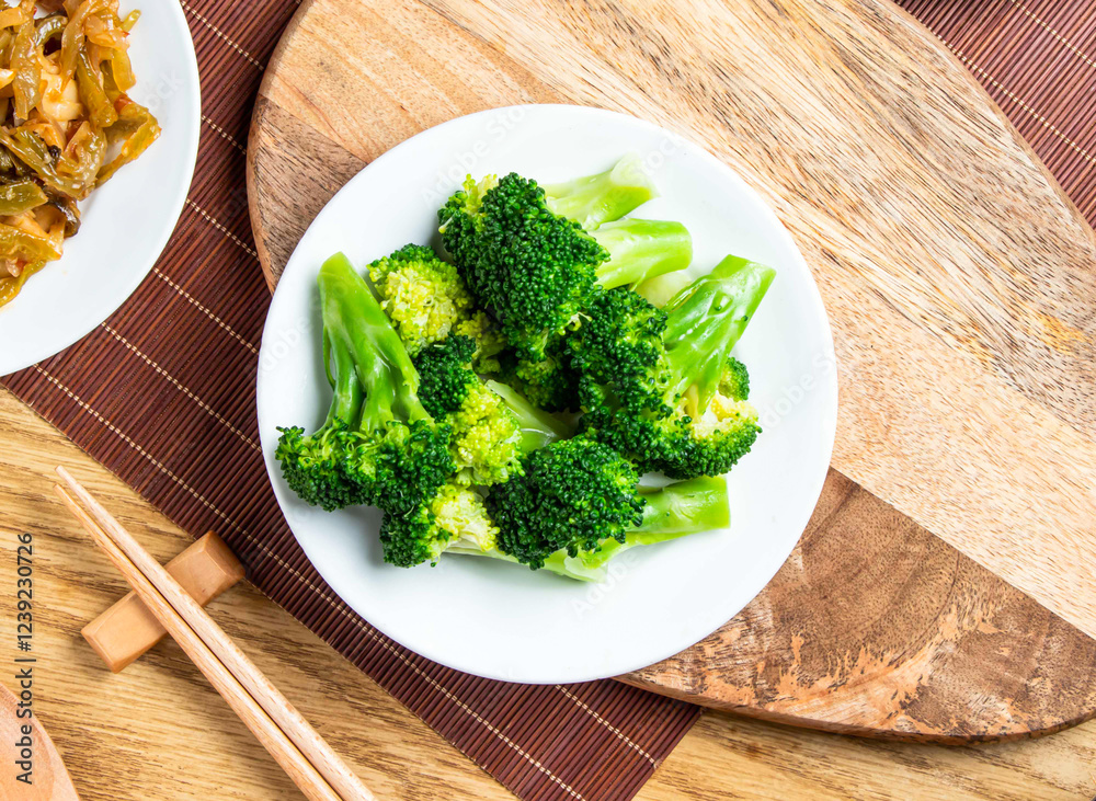 Fresh broccoli served in plate with chopsticks and spoon isolated on wooden board top view of taiwan food Fresh broccoli served in plate with chopsticks and spoon isolated on wooden board top view of taiwan food