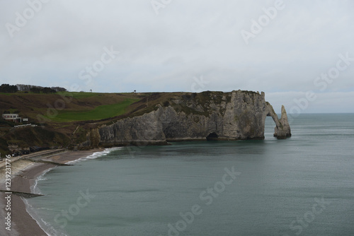 The white cliffs of Etretat appear almost serene under a cloudy sky, with no sign of harsh winter.