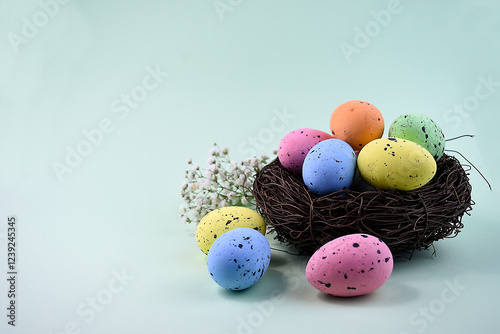 Easter nest with colorful painted eggs on a pastel mint background. photo