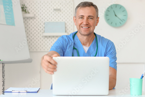 Mature doctor working with laptop at desk in medical office