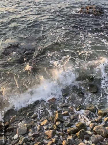 Vertical video of sea waves with foam at coastline with pebbles outdoor. Summer vacation season